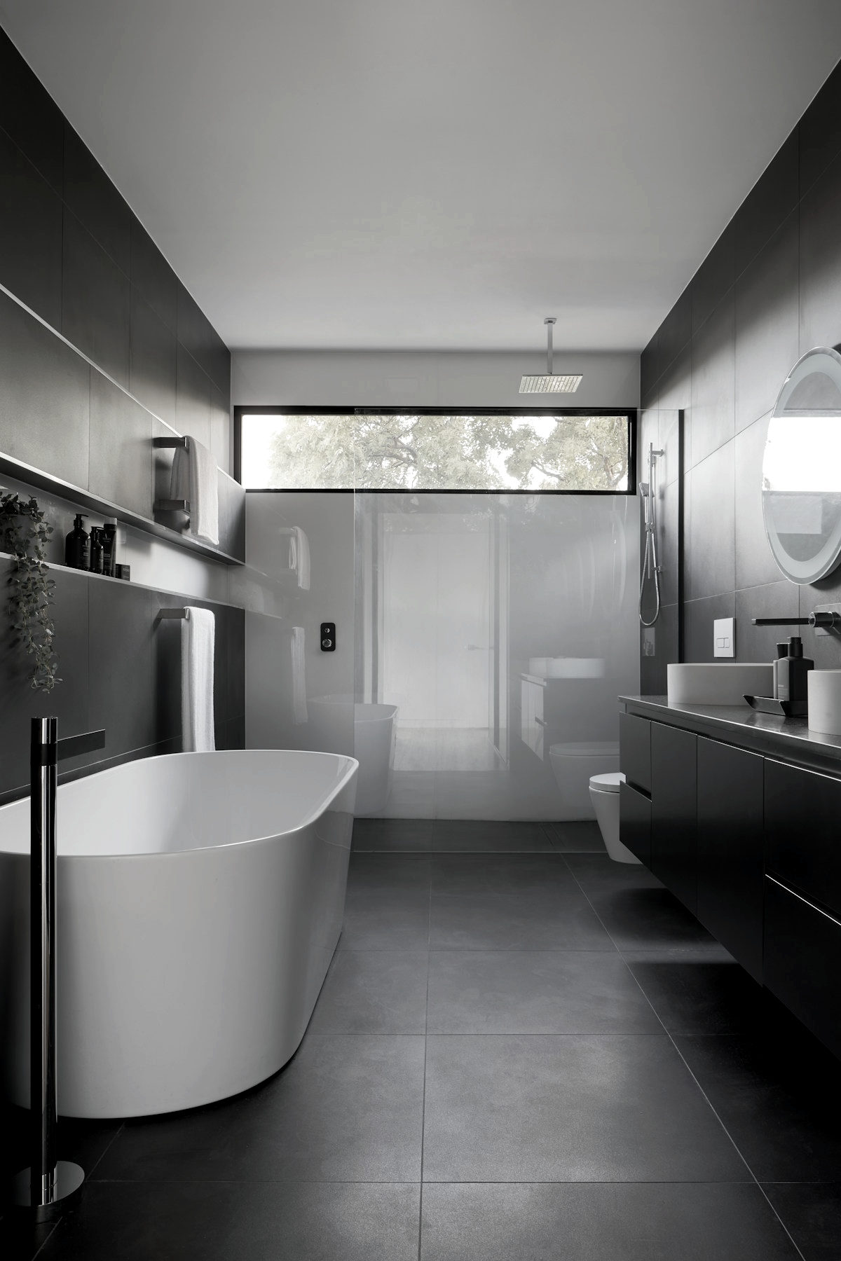 Bathroom in dark large-format tile with a long clerestory window above the shower